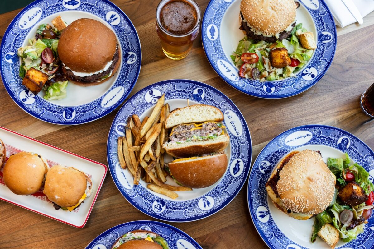 Overhead view of handcrafted burgers and crispy fries at Founding Farmers, ideal for burger lovers looking for the best burgers in Washington, DC. Plates also include fresh salads and cold beers for the ultimate meal.